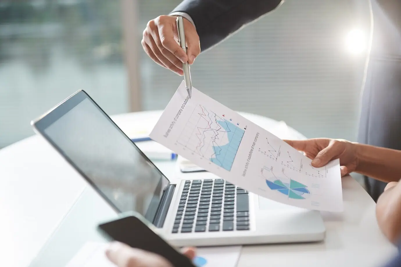 Équipe d’une entreprise moderne travaillant en coworking, utilisant des graphiques et un ordinateur portable dans un bureau.